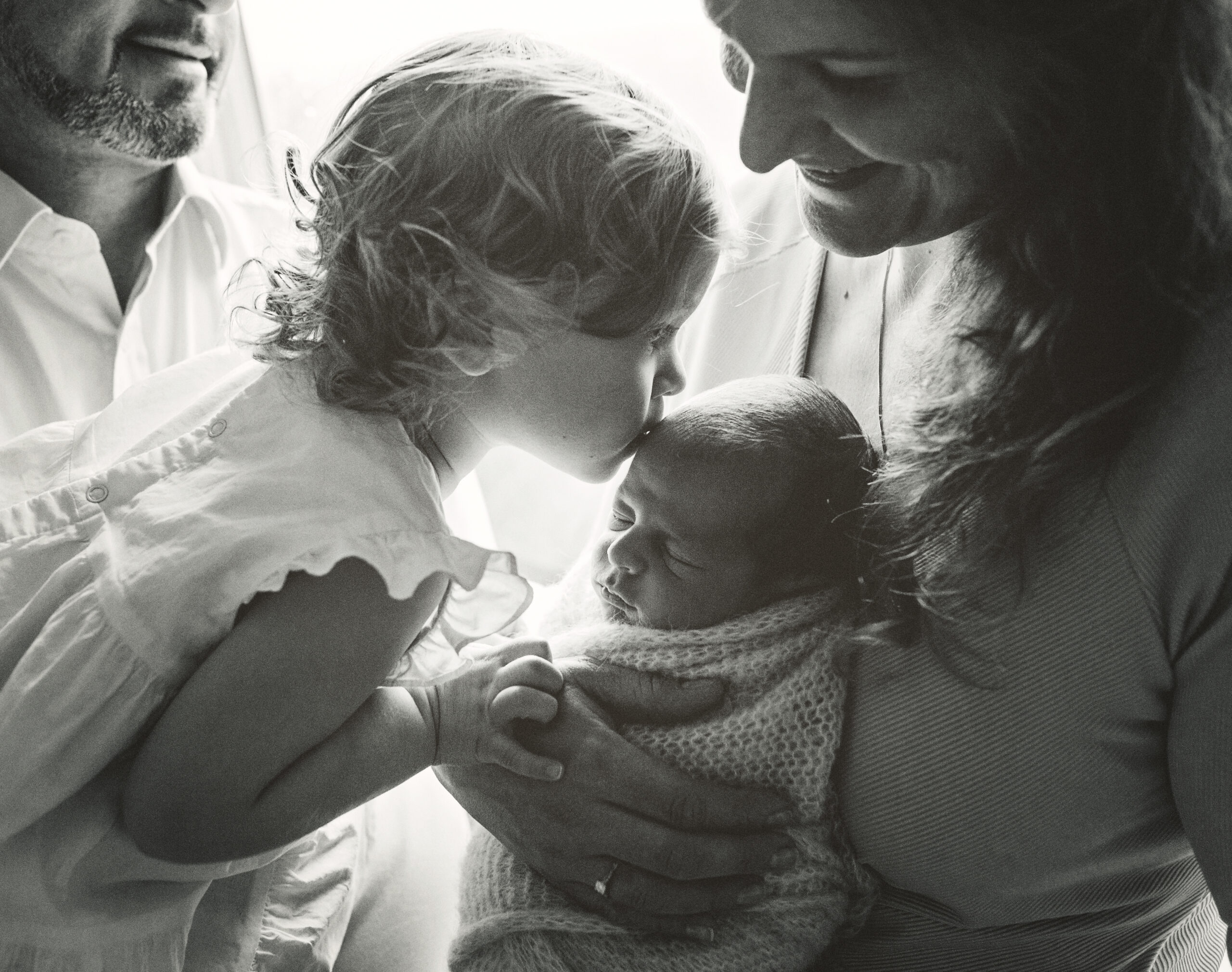 toddler sibling kissing newborn baby