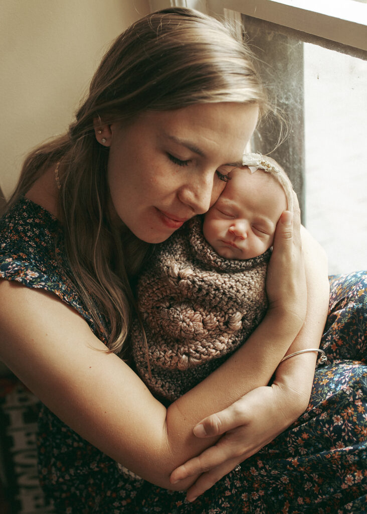 New Jersey newborn photography Mom hugging her newborn daughter swaddled in a crochet blanket in Morristown NJ