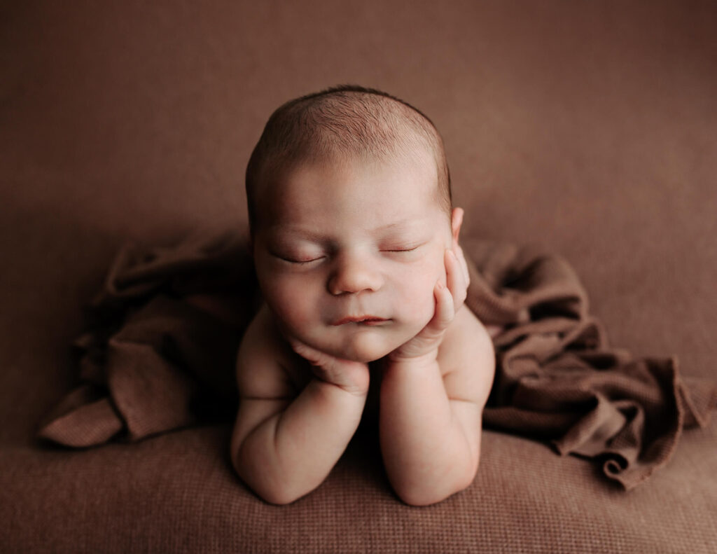 newborn baby boy on a brown backdrop photographed in Morristown NJ
