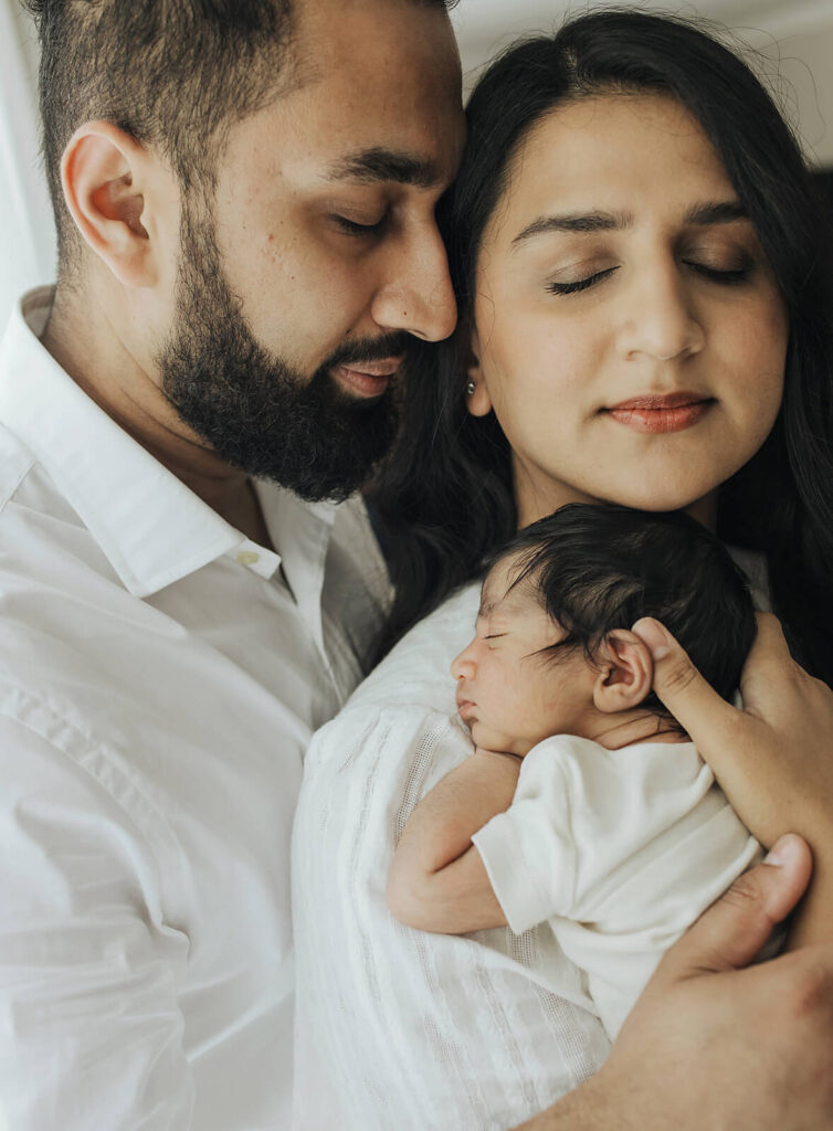 Mom and dad snuggling their newborn baby girl